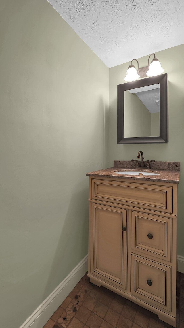 bathroom featuring baseboards, a textured ceiling, and vanity