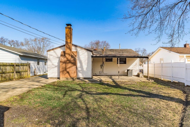 rear view of property featuring a patio area, a lawn, a chimney, and fence