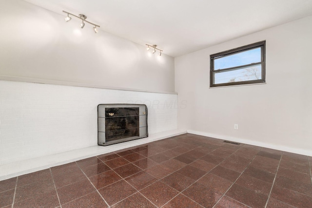 unfurnished living room with visible vents, granite finish floor, a fireplace, and baseboards