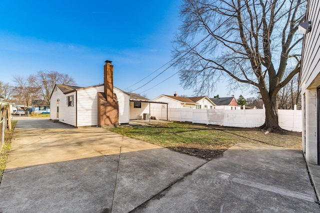 exterior space with driveway, a chimney, and fence