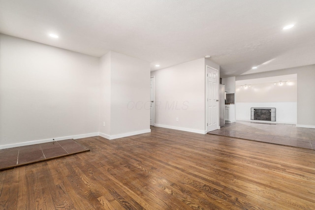 unfurnished living room featuring recessed lighting, a fireplace, baseboards, and wood finished floors