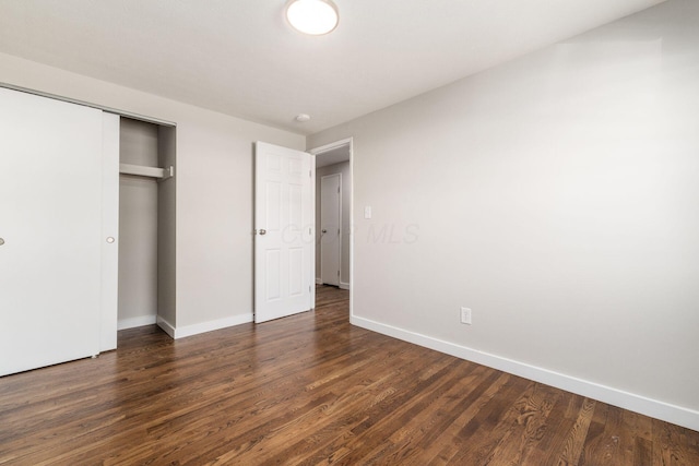 unfurnished bedroom featuring a closet, baseboards, and wood finished floors