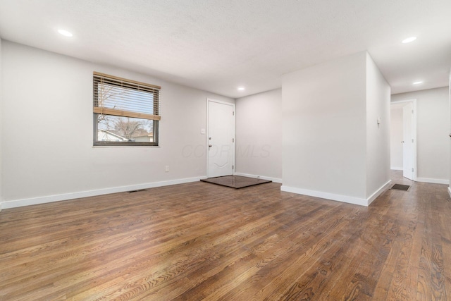 spare room featuring visible vents, recessed lighting, baseboards, and wood finished floors