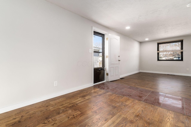 empty room with dark wood finished floors, baseboards, and a wealth of natural light