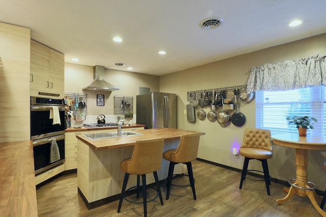 kitchen featuring visible vents, butcher block countertops, appliances with stainless steel finishes, wall chimney exhaust hood, and dark wood-style flooring