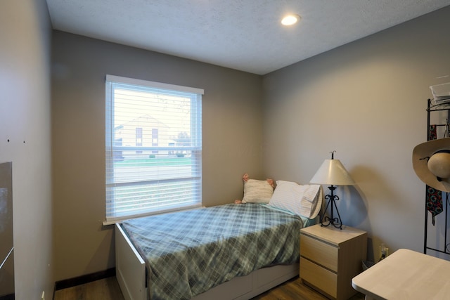 bedroom featuring a textured ceiling, baseboards, and dark wood-style flooring