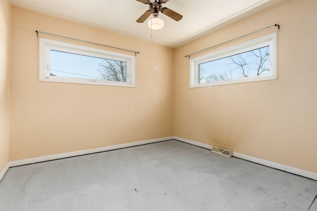 spare room featuring visible vents, a ceiling fan, concrete floors, and baseboards