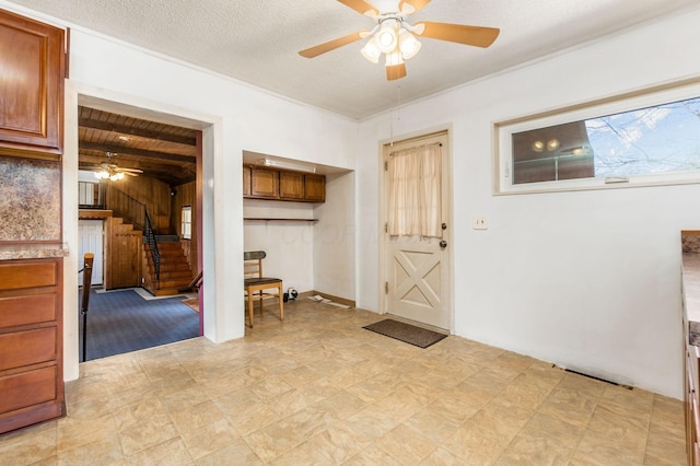 entryway featuring a textured ceiling, wood ceiling, ceiling fan, and stairs