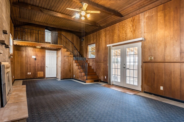 interior space with beamed ceiling, french doors, stairway, wood walls, and wooden ceiling