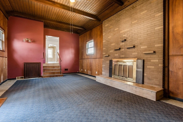 unfurnished living room with visible vents, carpet floors, beam ceiling, a fireplace, and wooden ceiling