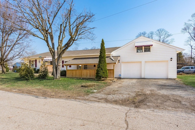 view of front of house featuring a front yard, roof with shingles, and driveway