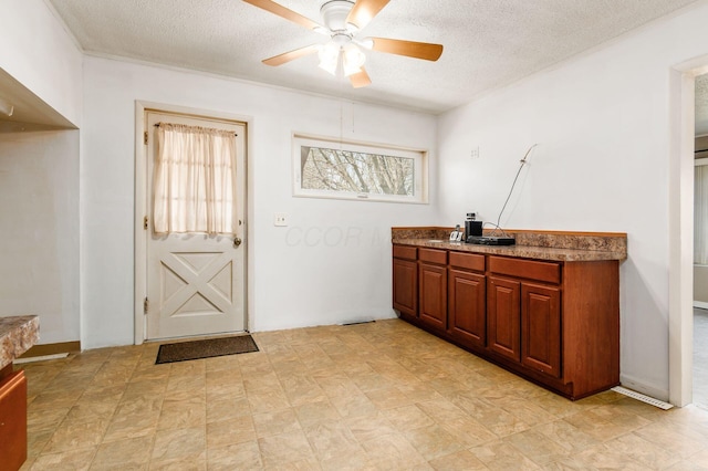 interior space featuring a textured ceiling, brown cabinetry, and ceiling fan