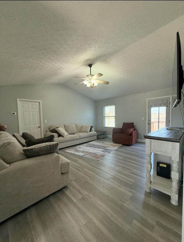 living room with vaulted ceiling, a textured ceiling, a ceiling fan, and wood finished floors