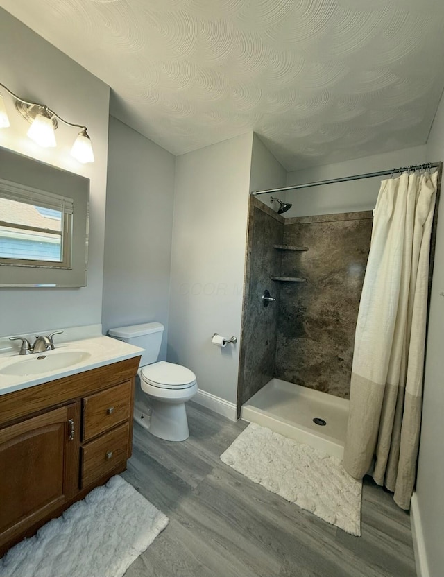 full bath with toilet, wood finished floors, a shower with shower curtain, baseboards, and vanity