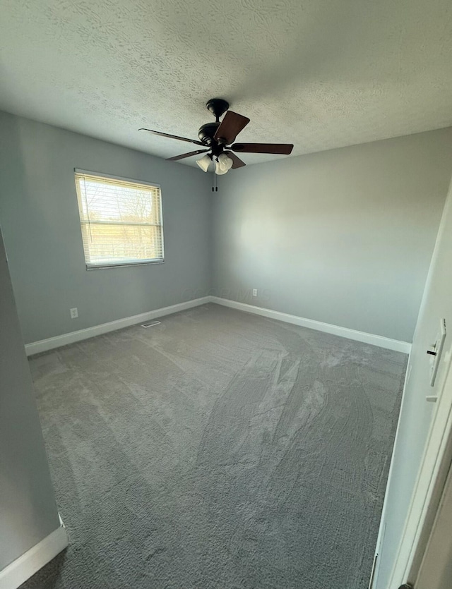 carpeted spare room with a textured ceiling, baseboards, and a ceiling fan