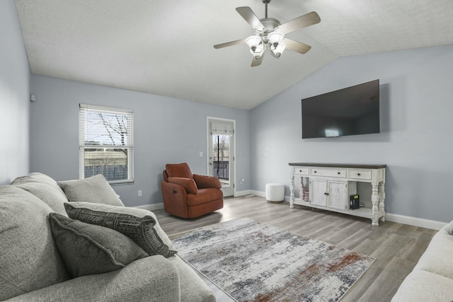 living area with baseboards, lofted ceiling, a ceiling fan, and wood finished floors