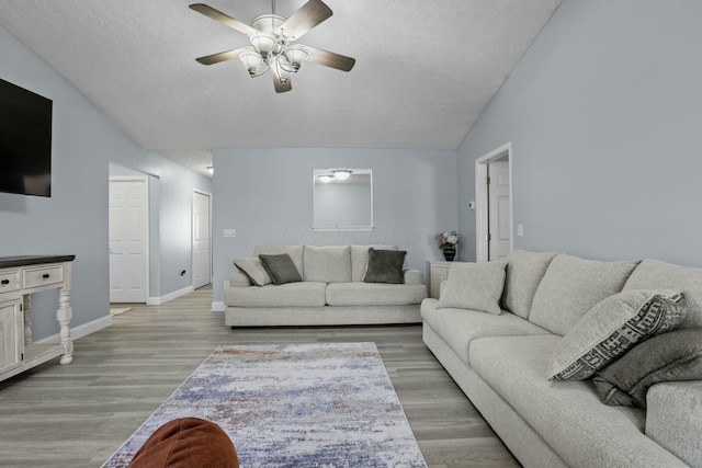 living room with light wood-style flooring, a textured ceiling, baseboards, lofted ceiling, and ceiling fan