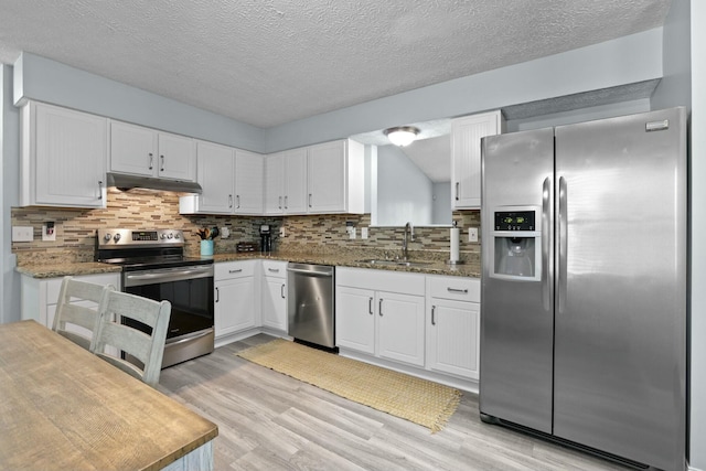 kitchen featuring a sink, stainless steel appliances, white cabinets, under cabinet range hood, and light wood-type flooring