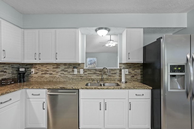 kitchen with decorative backsplash, stainless steel appliances, a textured ceiling, white cabinetry, and a sink