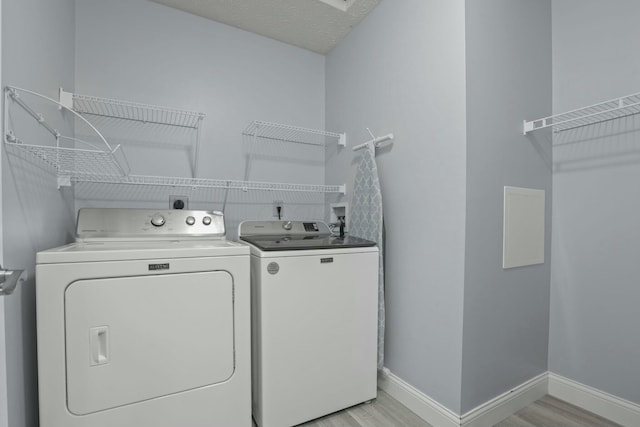 laundry room with laundry area, washing machine and dryer, light wood-style floors, and baseboards