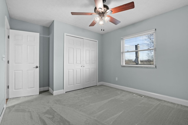 unfurnished bedroom with a textured ceiling, a closet, carpet flooring, baseboards, and ceiling fan