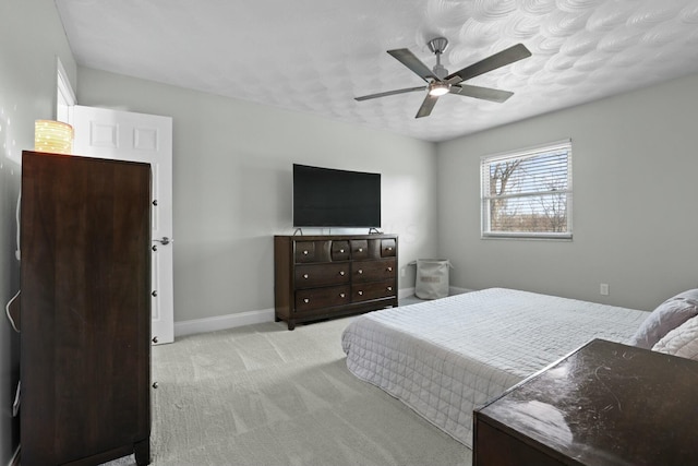 bedroom featuring light carpet, a ceiling fan, and baseboards