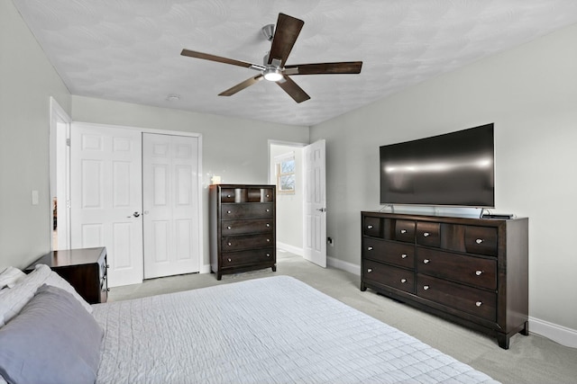 bedroom with ceiling fan, light colored carpet, a closet, and baseboards