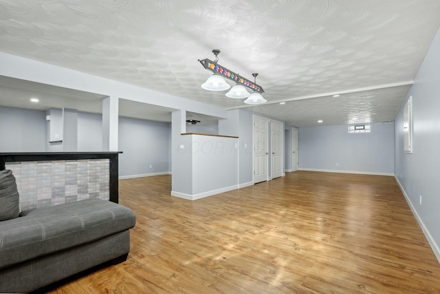 living area featuring a dry bar, light wood-style floors, baseboards, and a textured ceiling