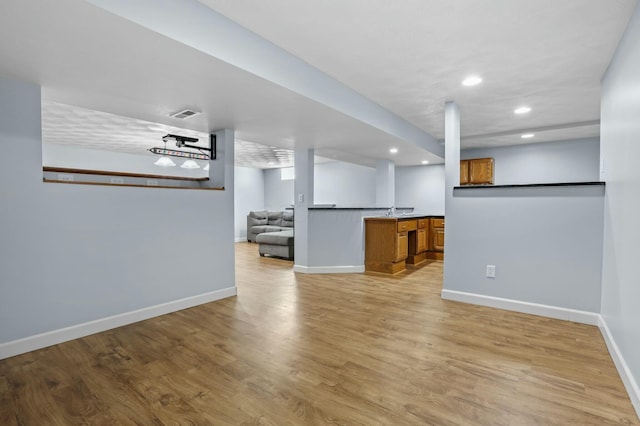 interior space with visible vents, baseboards, light wood finished floors, recessed lighting, and bar area