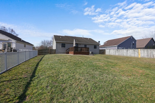 back of property with a deck, a yard, and a fenced backyard