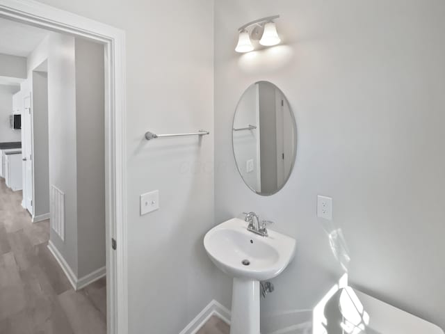 half bath featuring visible vents, baseboards, and wood finished floors