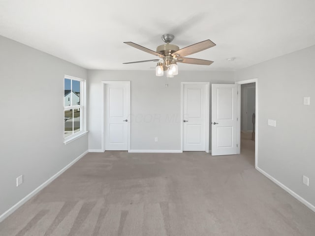 unfurnished bedroom featuring baseboards, light carpet, and ceiling fan