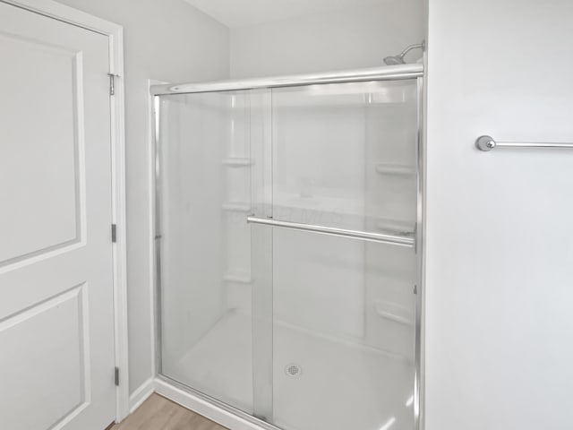 bathroom with wood finished floors and a stall shower