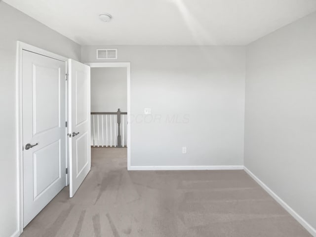 carpeted empty room with baseboards and visible vents