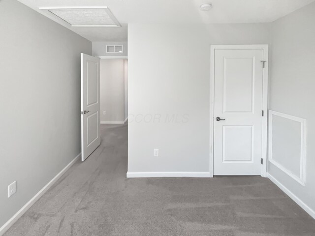 unfurnished bedroom with attic access, baseboards, visible vents, and carpet floors