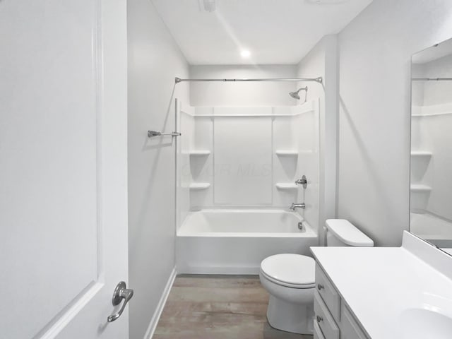 bathroom with toilet, wood finished floors, shower / bathing tub combination, baseboards, and vanity