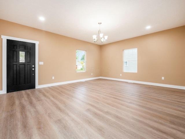 unfurnished room with recessed lighting, baseboards, light wood-type flooring, and a chandelier