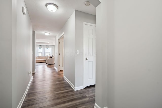 hall with dark wood-style floors and baseboards