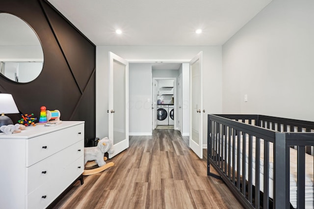 bedroom featuring baseboards, light wood-style flooring, a nursery area, french doors, and independent washer and dryer