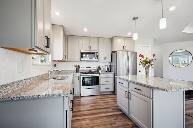 kitchen featuring light stone countertops, dark wood finished floors, gray cabinets, stainless steel appliances, and a sink