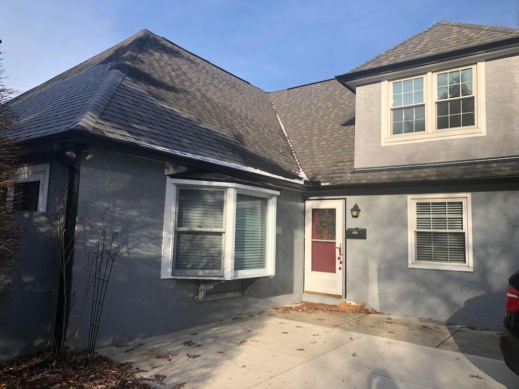 exterior space featuring stucco siding, a shingled roof, and a patio area