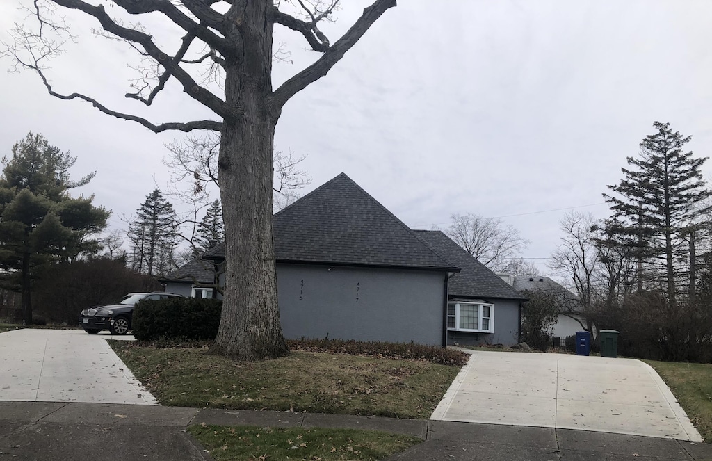 view of home's exterior with stucco siding, driveway, and a shingled roof