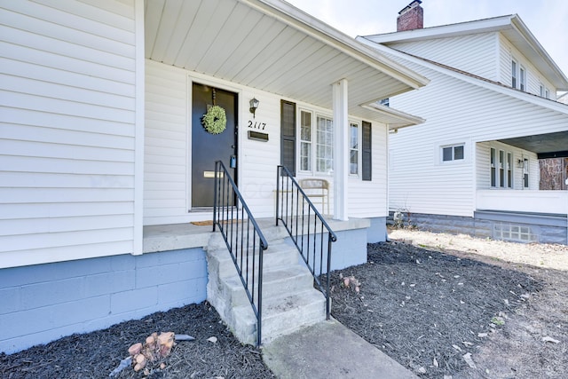 doorway to property featuring a porch and a chimney