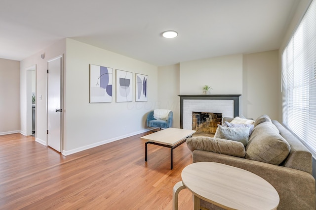 living area featuring light wood-style flooring, a fireplace, and baseboards