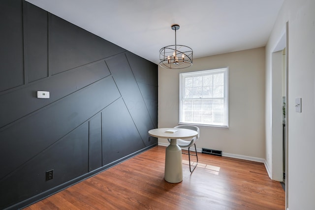 dining space with baseboards, wood finished floors, visible vents, and a chandelier