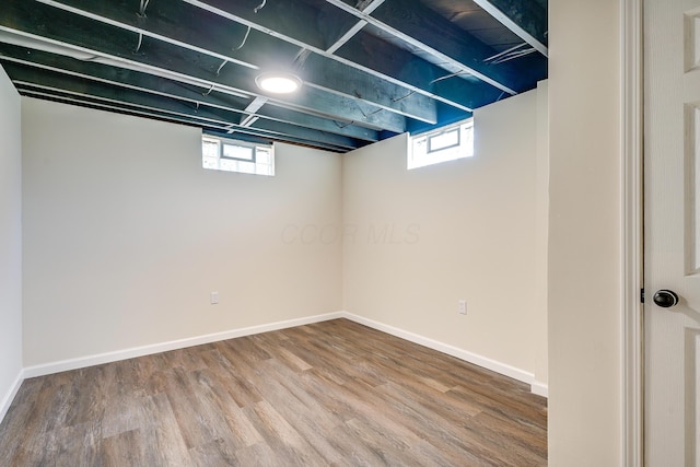 basement featuring a healthy amount of sunlight, baseboards, and wood finished floors