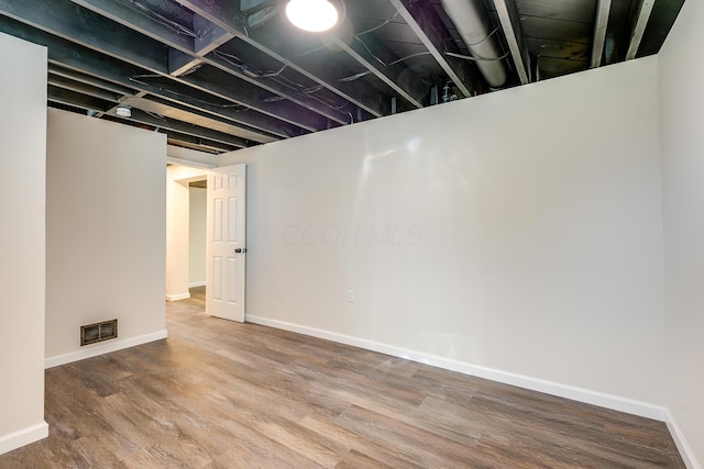 finished basement with visible vents, baseboards, and wood finished floors