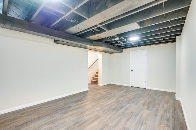 finished basement with stairs, wood finished floors, and baseboards