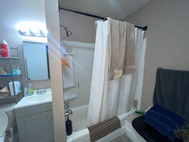 full bath featuring vanity, shower / bathtub combination with curtain, and a textured ceiling