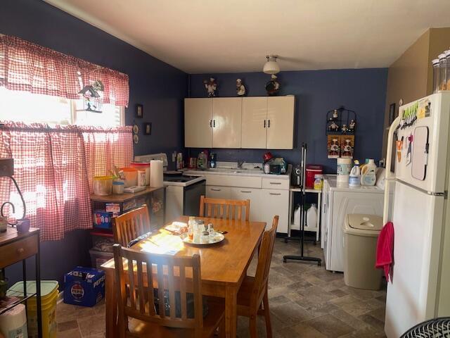 kitchen with white cabinets, stone finish flooring, light countertops, and freestanding refrigerator